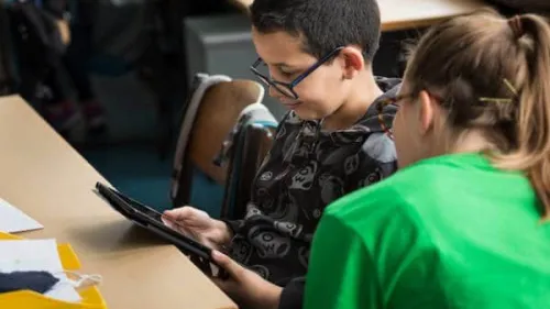 Two people viewing a computer tablet while seated at a table.