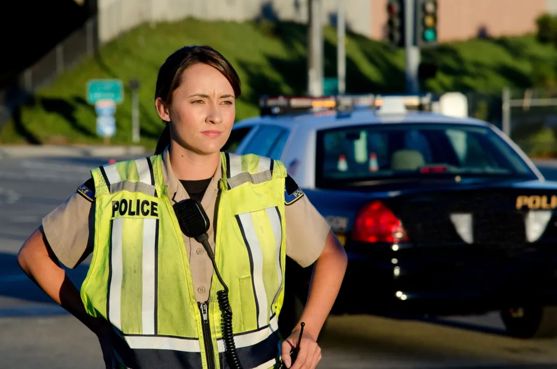 A police officer standing in the road next to a police car