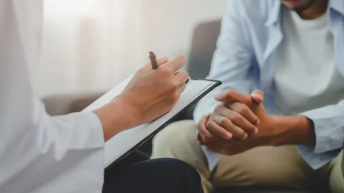 Photo of mental health professional taking notes from a male patient