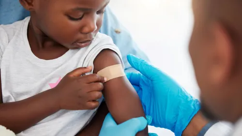 Photo of a doctor and a child with a band-aid on her arm after getting a vaccination.