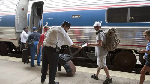 Passengers board a train. A conductor checks a passenger's ticket as he boards the train.