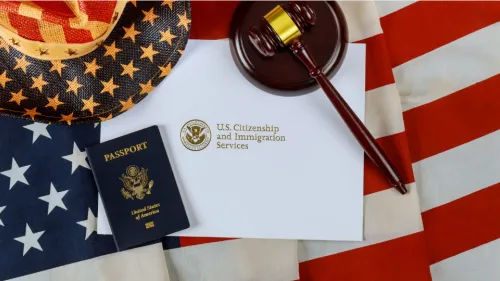 A U.S. passport, a judge's gavel, and an envelope from U.S. Citizenship and Immigration Services are laid on an American flag.