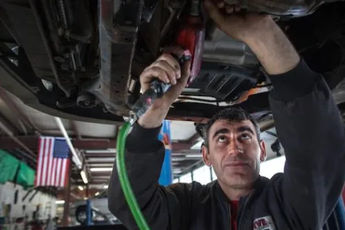 Man working on the underside of an automobile.
