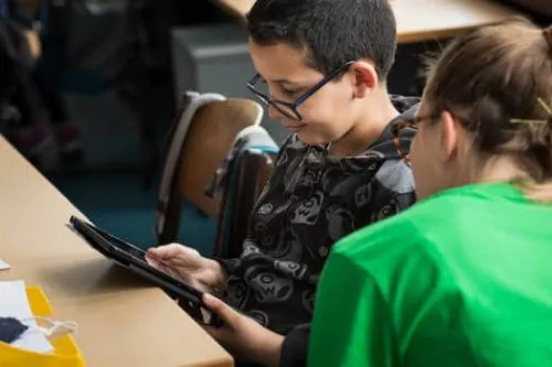 Two people viewing a computer tablet while seated at a table.