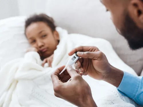 Fotografía de un padre leyendo un termómetro para comprobar si su hija tiene fiebre.