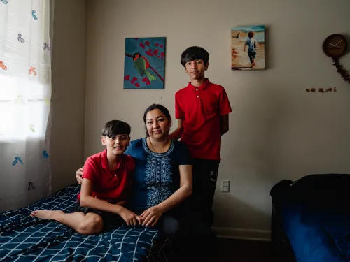 Photo of a woman and two boys in a bedroom with two beds.