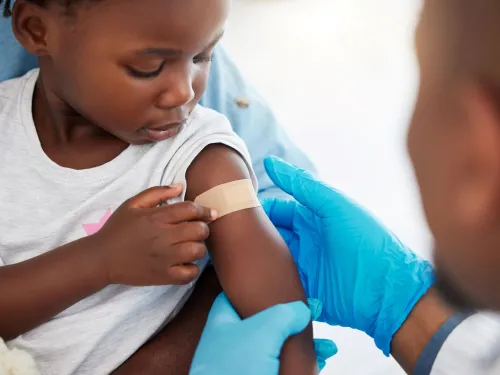 Photo of a doctor and a child with a band-aid on her arm after getting a vaccination.