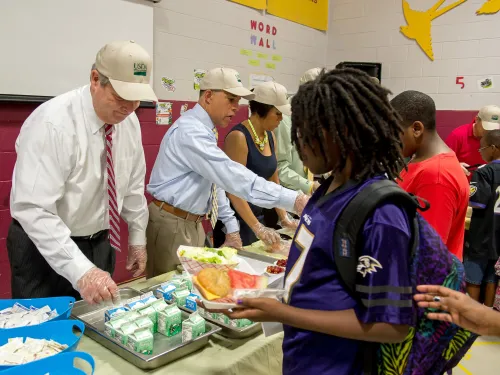 Photo of adults providing free summer meals to students.