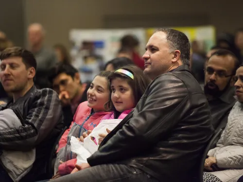 Photo of adults and children at an educational community event.