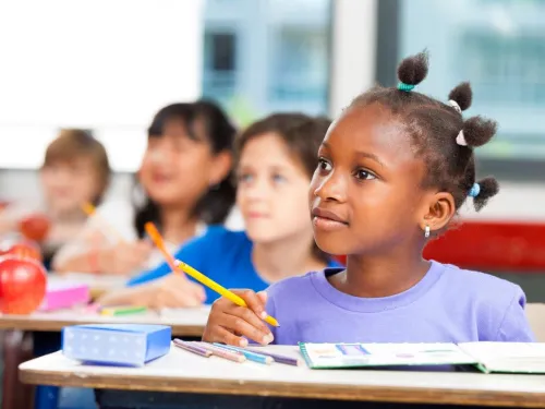 Child sitting at desk learning with classmates