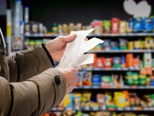 A person in a grocery store holding several receipts