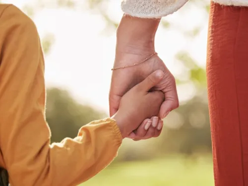 An adult and a child holding hands
