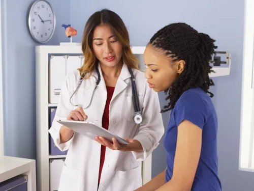 Una doctora y una paciente están revisando juntas la información del paciente