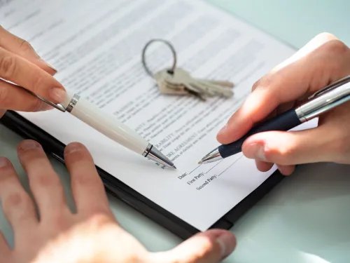 Photo of a person signing a lease for a property.