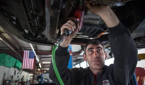Man working on the underside of an automobile.