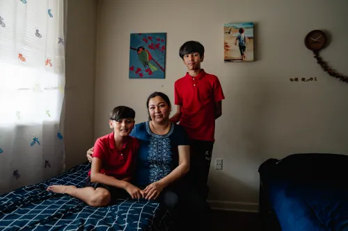 Photo of a woman and two boys in a bedroom with two beds.