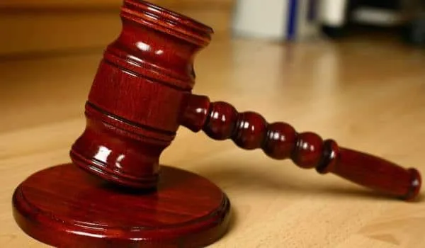 A wooden gavel resting on its sound block, symbolizing authority and justice. The gavel is polished and placed on a wooden surface.