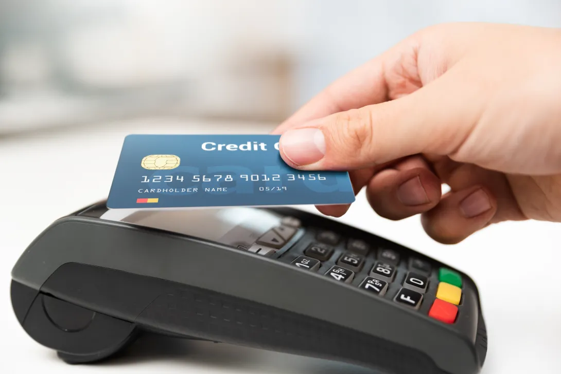 Photo of a person using their credit card on a credit card reader