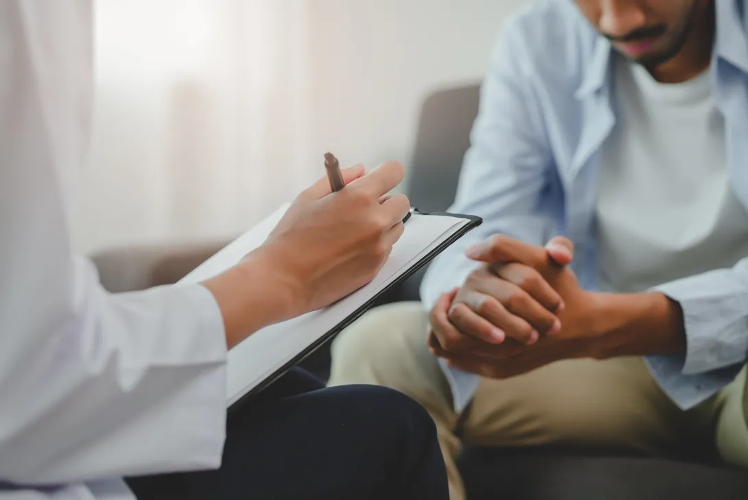 Photo of mental health professional taking notes from a male patient