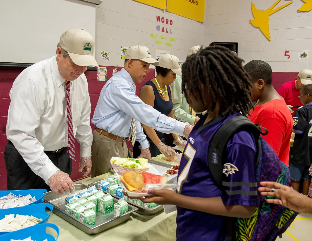 Photo of adults providing free summer meals to students.