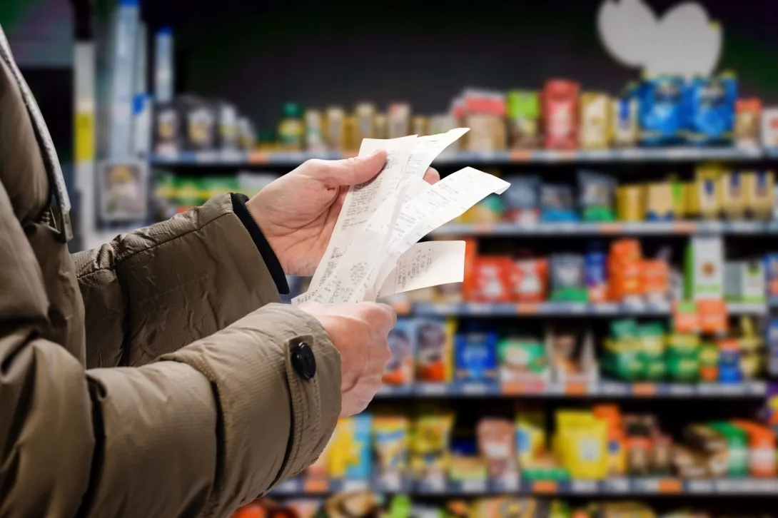 A person in a grocery store holding several receipts
