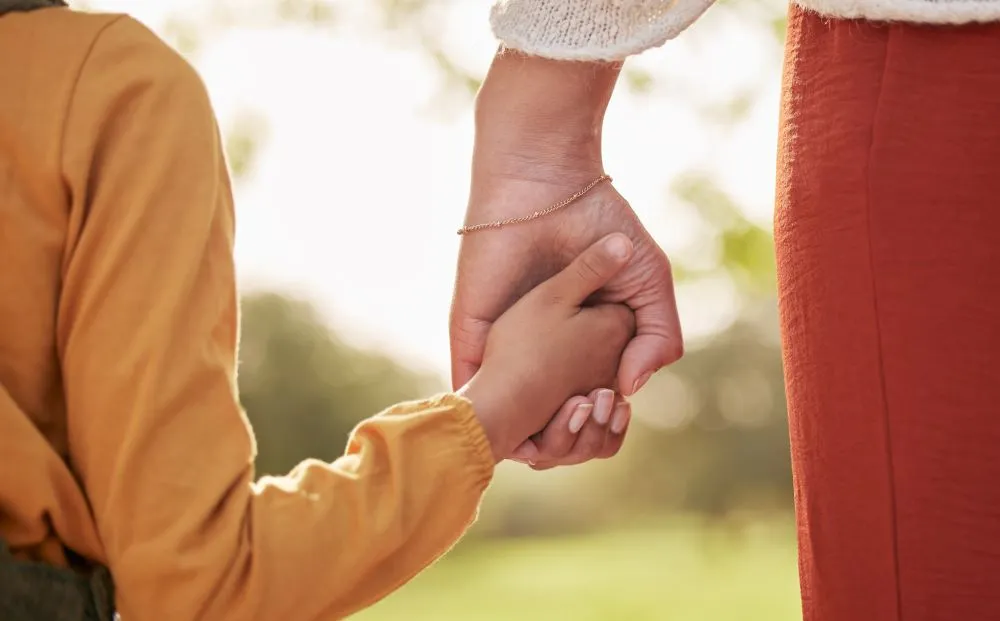 An adult and a child holding hands