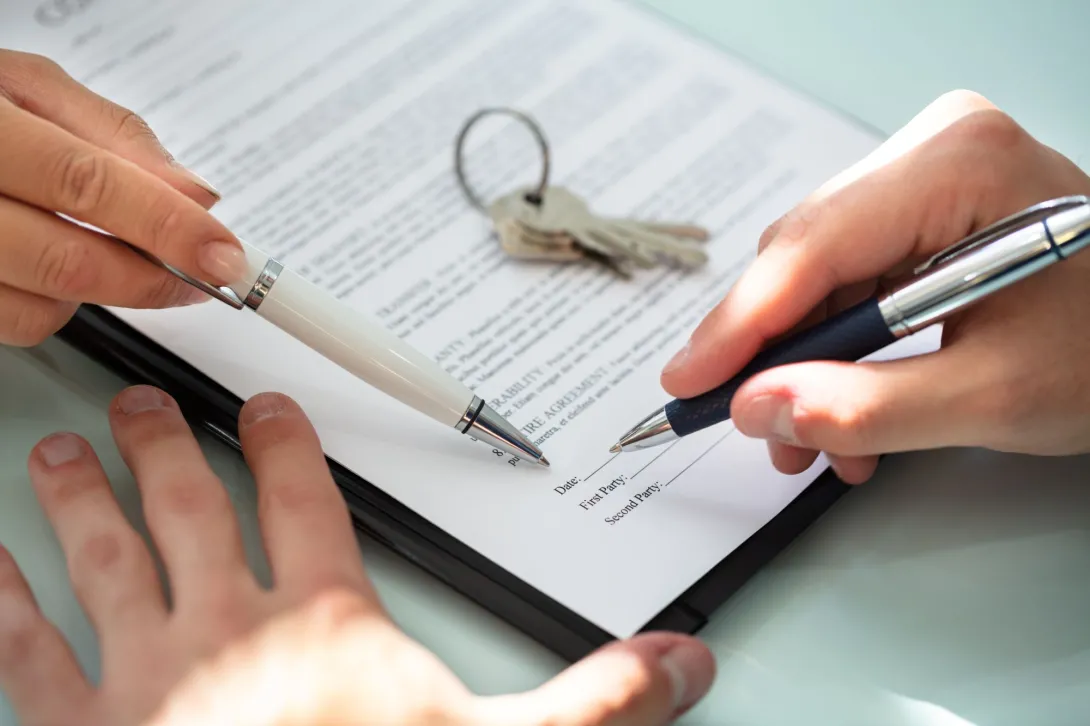 Photo of a person signing a lease for a property.